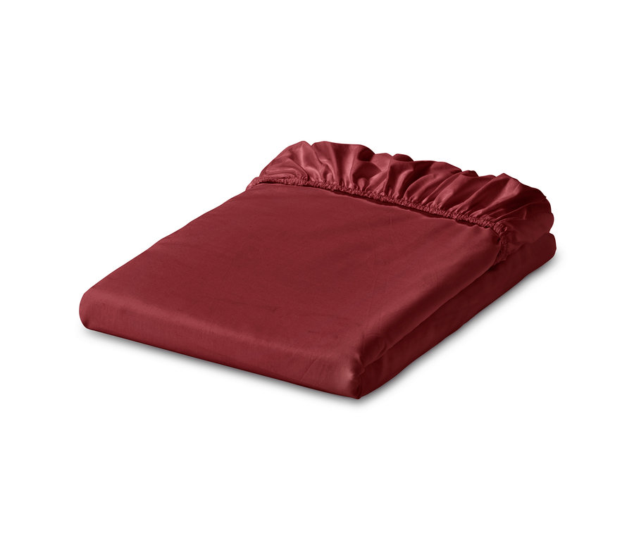 Zložené tmavočervené džersejové napínacie prestieradlo.