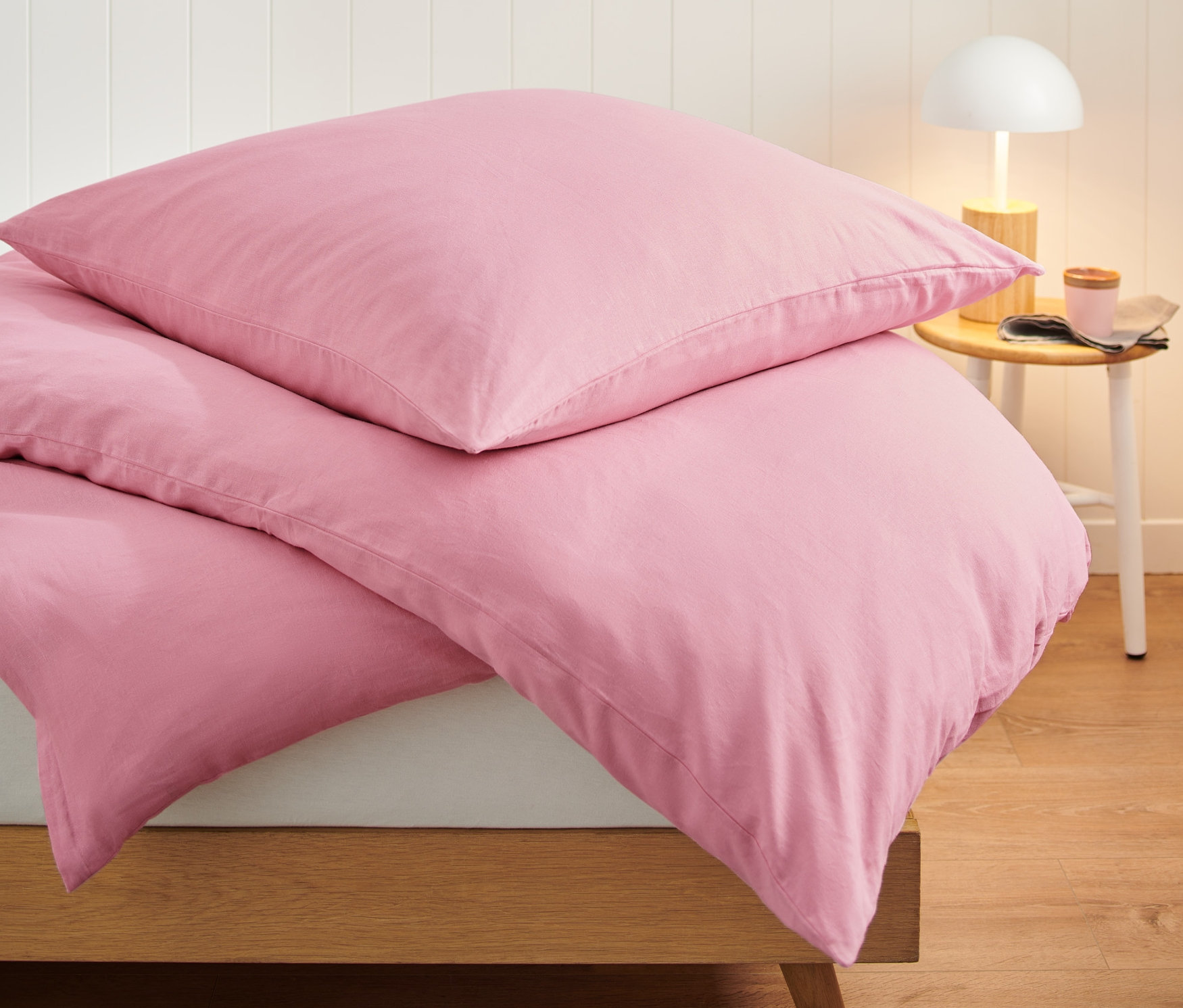 Detail ľanovej posteľnej bielizne ružovej farby štandardnej a nadmernej veľkosti na posteli.