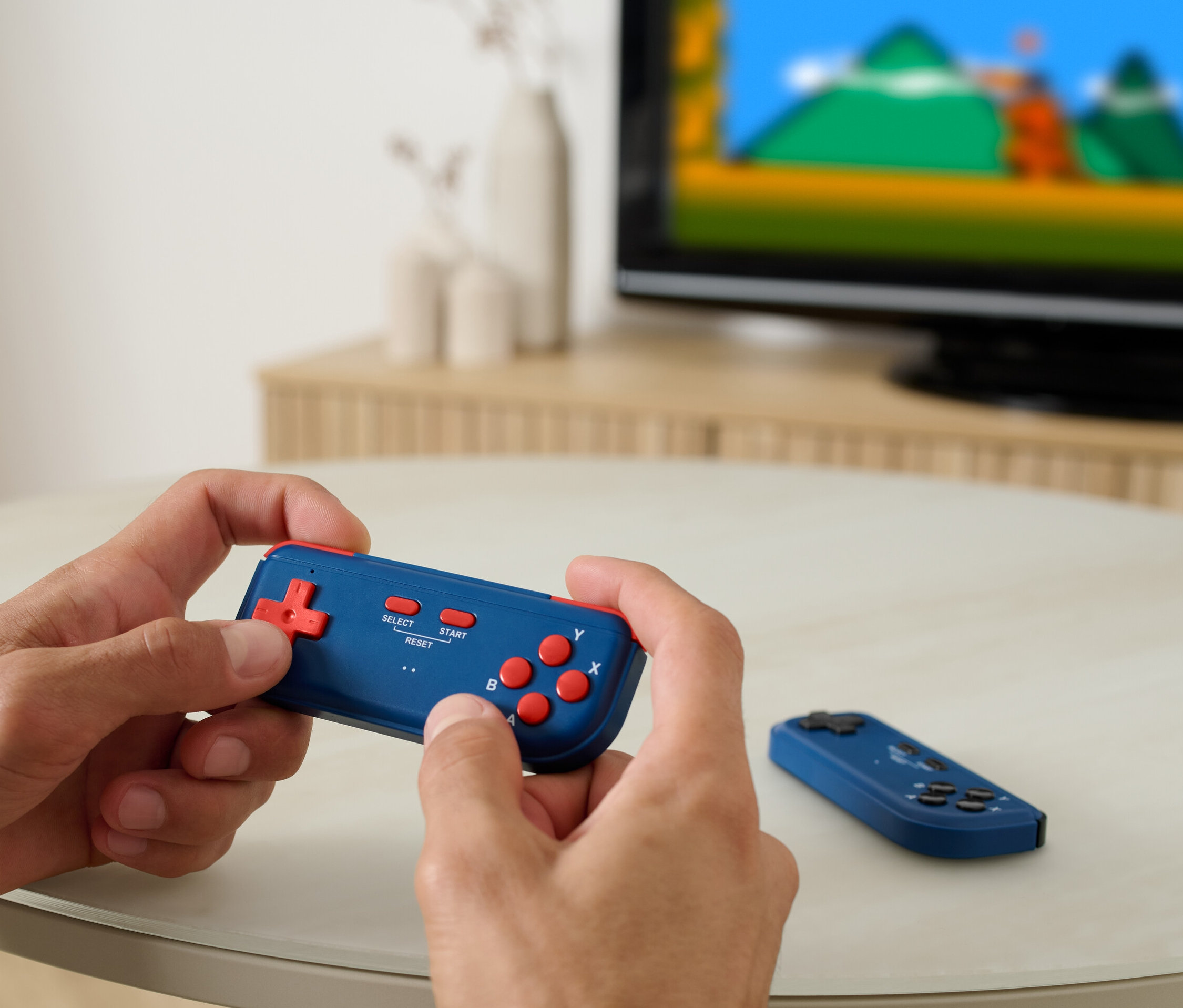 Muž hrá na retro TV hracej konzole, v pozadí je vidieť televízor.