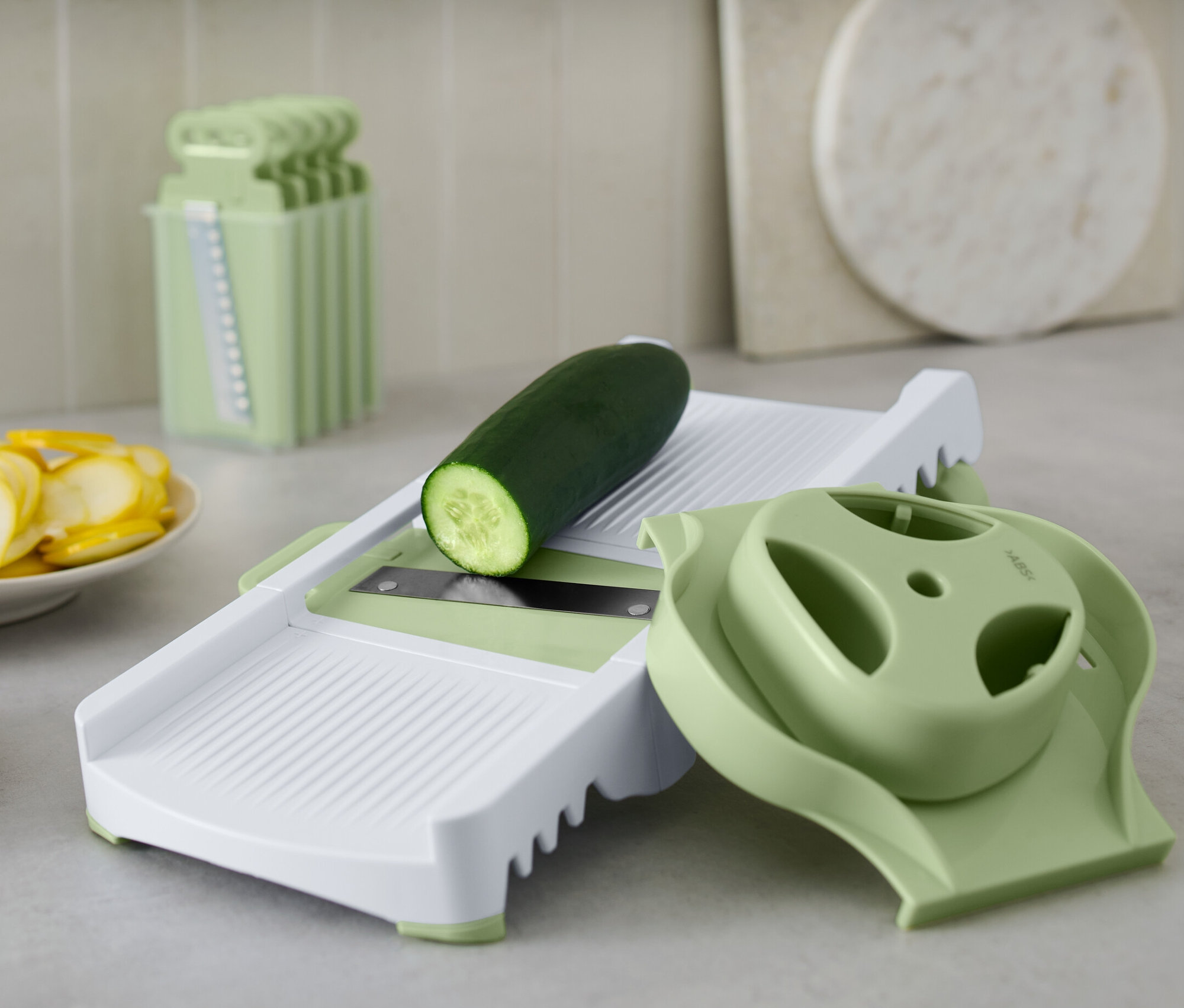 Uhorka leží na multifunkčnom strúhadle. Vedľa sú nakrájané uhorky a cukety.
