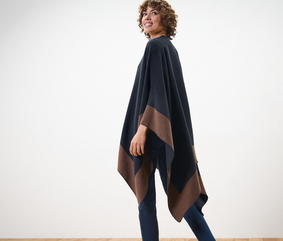 Žena pózuje v obojstrannom ponču.
