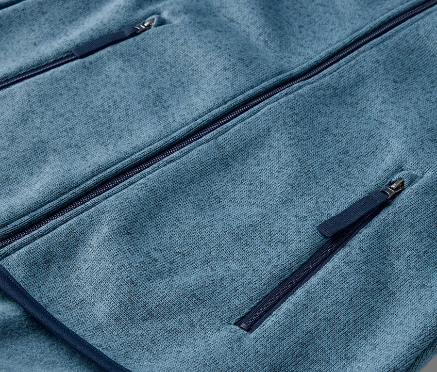 Detail modrej bundy z pleteného flaušu s vreckami na zips.