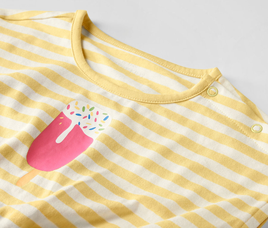 Detail detského overalu so žltými a bielymi pruhmi a potlačou nanuku.