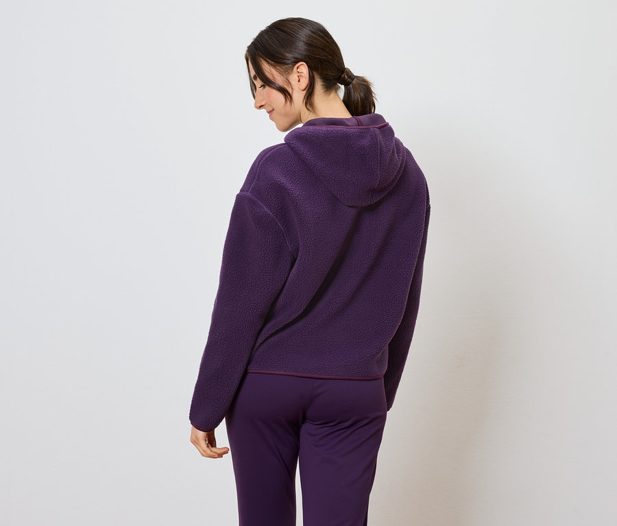 Žena v fialovej súprave s kapucňou, pohľad zozadu.