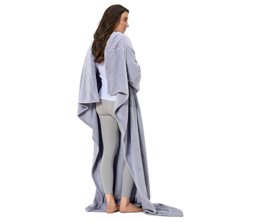 Žena stojí chrbtom k fotoaparátu, zabalená v sivej deke.