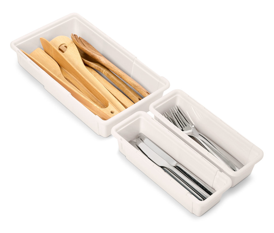 Súpravy bielych organizérov do zásuviek s dreveným a strieborným kuchynským náčiním.
