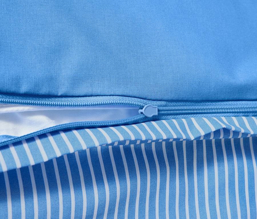 Detail bavlnenej posteľnej bielizne renforcé so zipsom a modro-bielym pruhovaným vzorom.