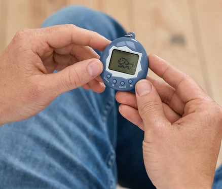Muž drží v rukách modré Tamagotchi.