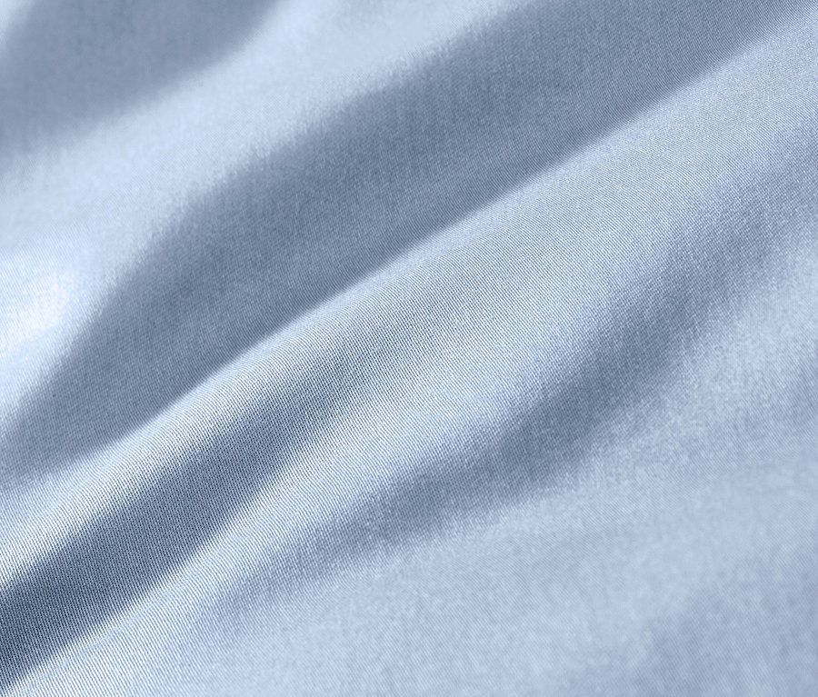 Detailný záber na svetlomodrú posteľnú bielizeň z bavlny a saténu v nadmernej veľkosti.