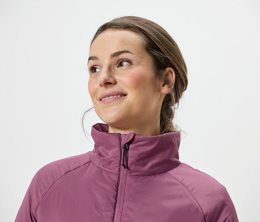 Žena s hnedými vlasmi a ružovou bundou sa pozerá doprava.