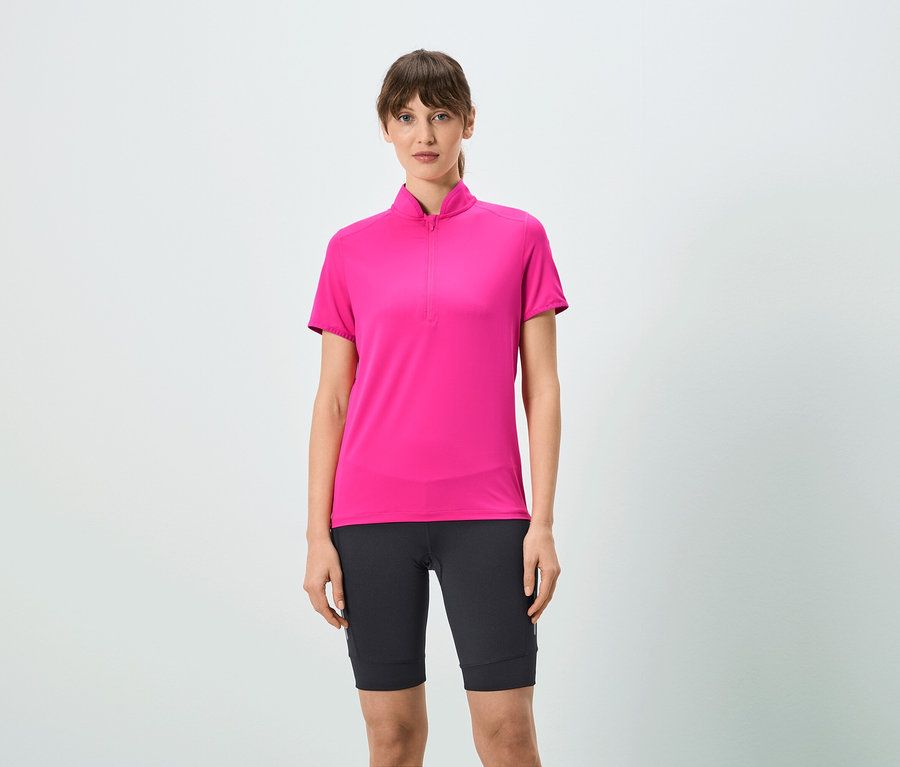 Žena má na sebe ružové tričko s krátkym zipsom a čierne šortky.