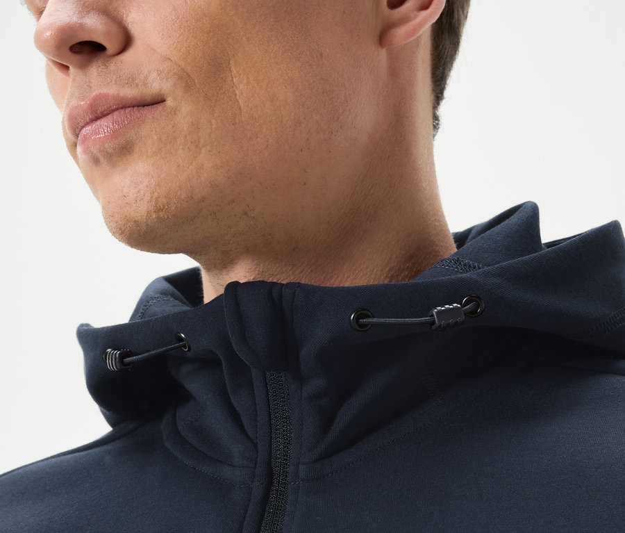 Detail muža v tmavomodrej mikine s kapucňou na zips.