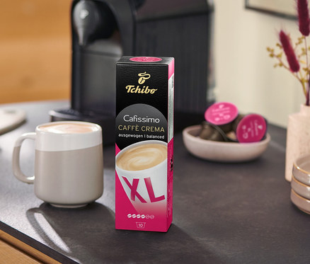 Na linke stojí kávovar vedľa balenia Caffè Crema Wake Up XL – 80 kapsúl a šálky.