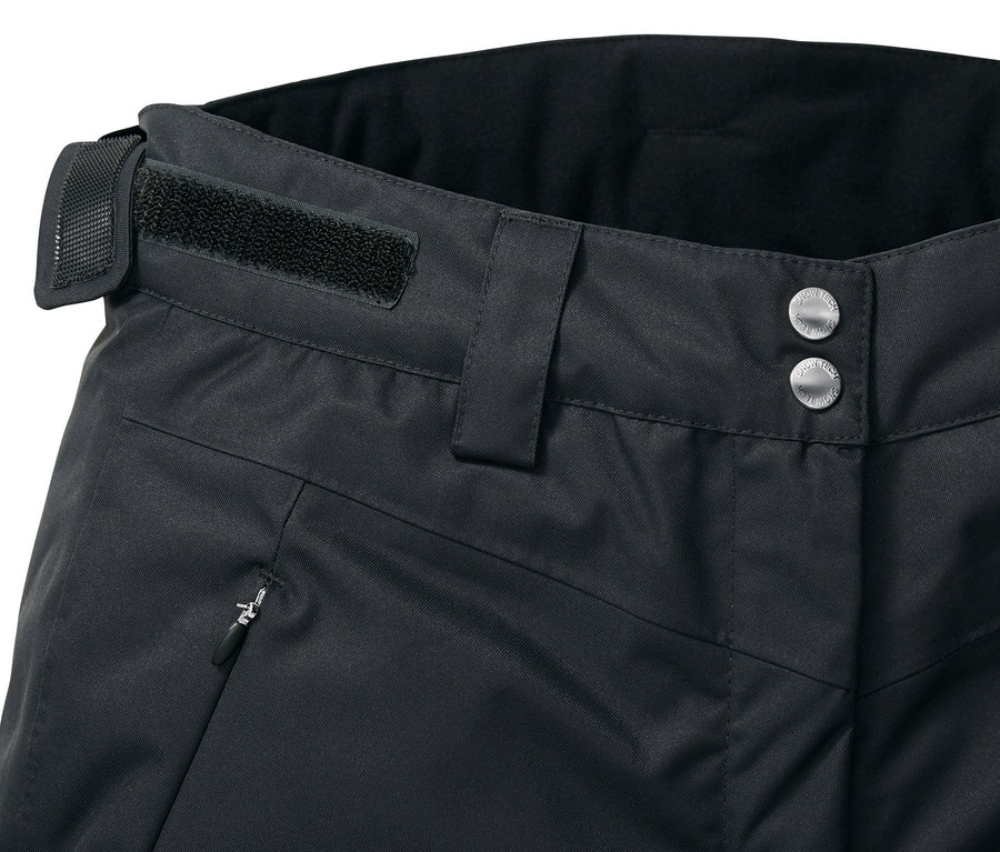 Detail čiernych lyžiarskych nohavíc so zapínaním na gombíky, pútkom na opasok a vreckom na zips.