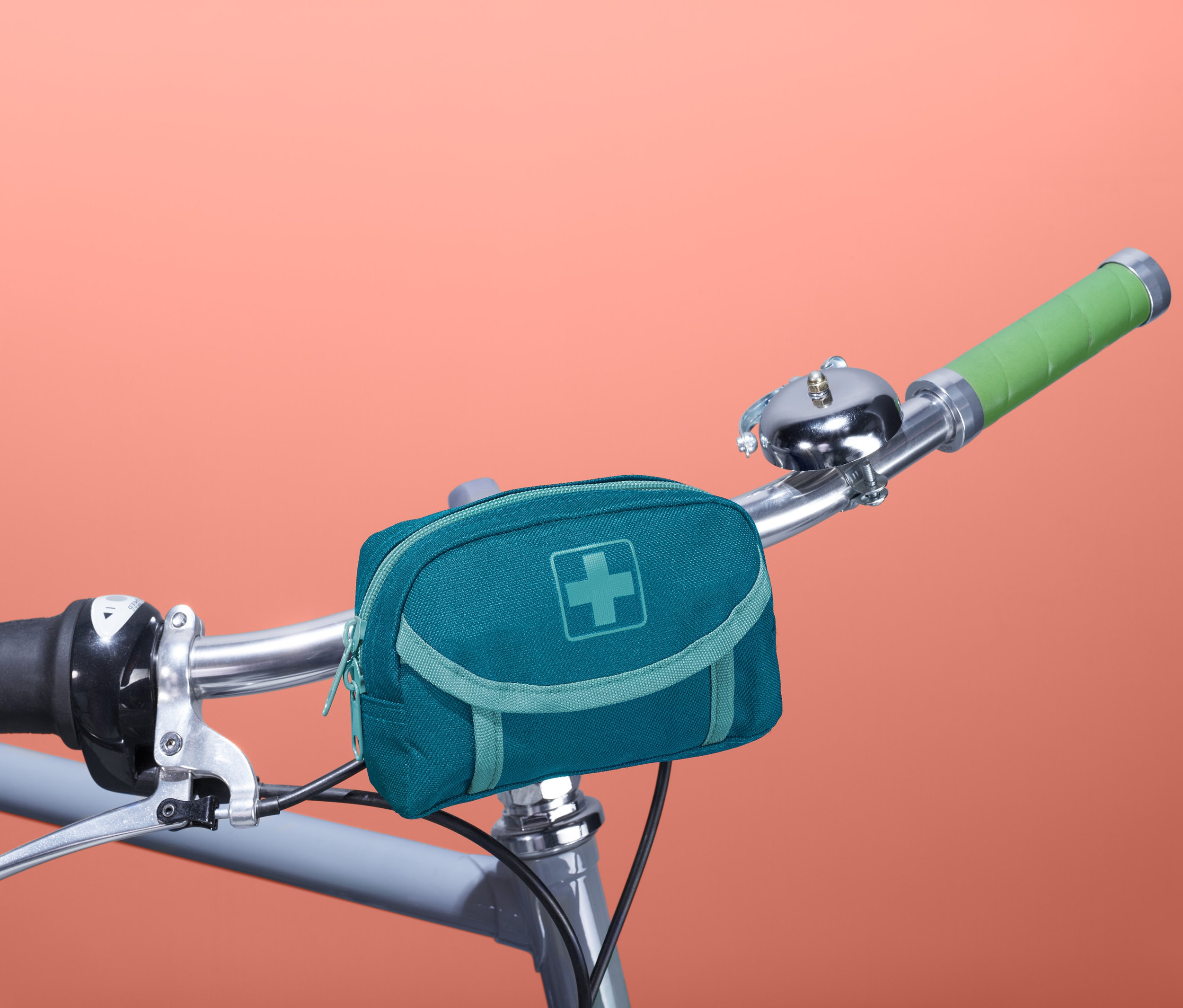 Na riadidlách bicykla je pripevnená modrozelená lekárnička.
