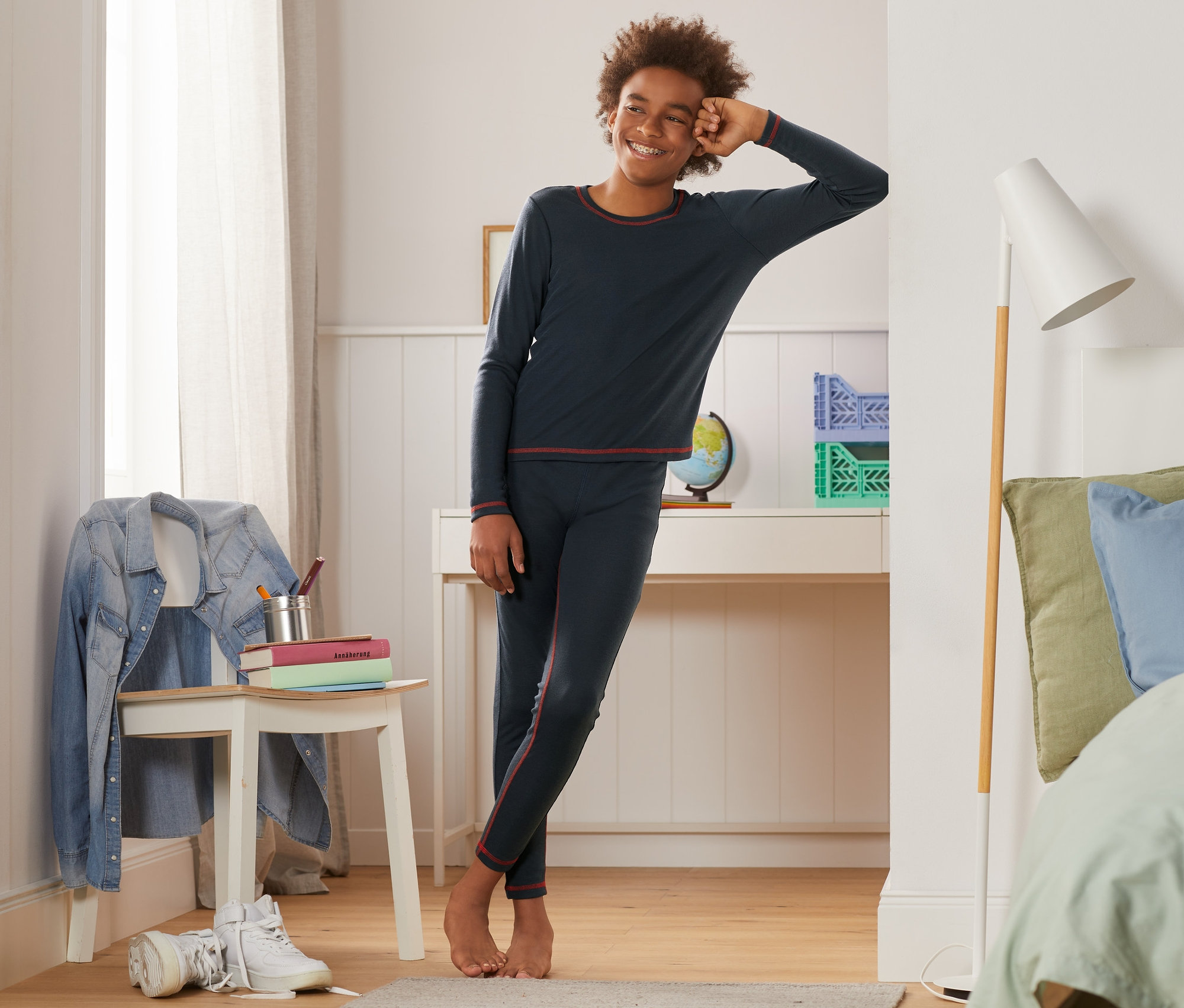 Chlapec sa opiera o stenu v tmavomodrej bezšvovej funkčnej spodnej bielizni.