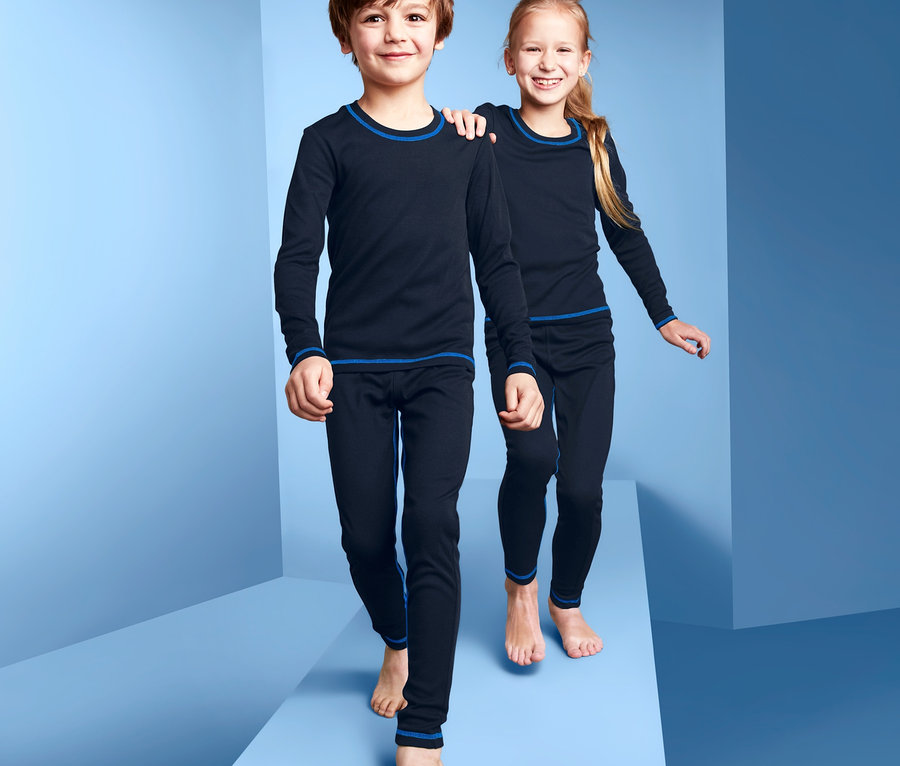 Chlapec a dievča kráčajú po modrom povrchu a majú na sebe funkčnú spodnú bielizeň.