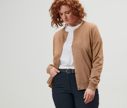 Žena má na sebe kardigán z jemného úpletu, kožený opasok a tmavomodré bengalínové nohavice.