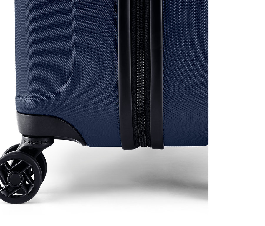 Detail modrého škrupinového kufra so zipsom a kolieskami.