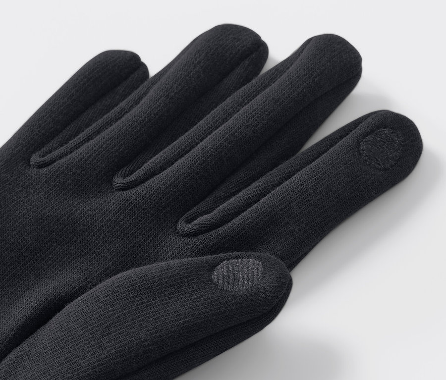Detail rukavice z teplákoviny čiernej farby na svetlom pozadí.