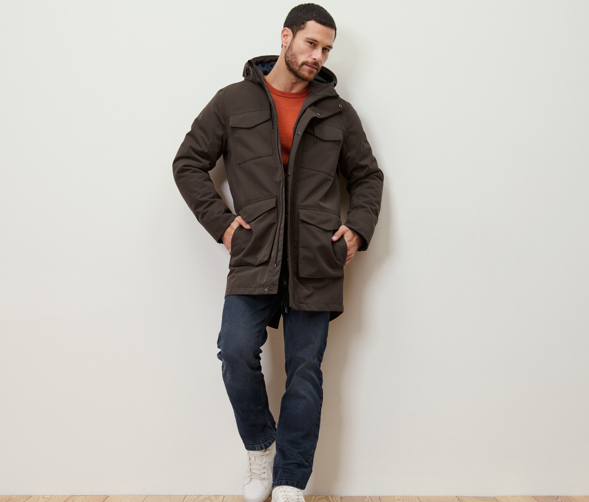 Muž opretý o stenu má na sebe parku.