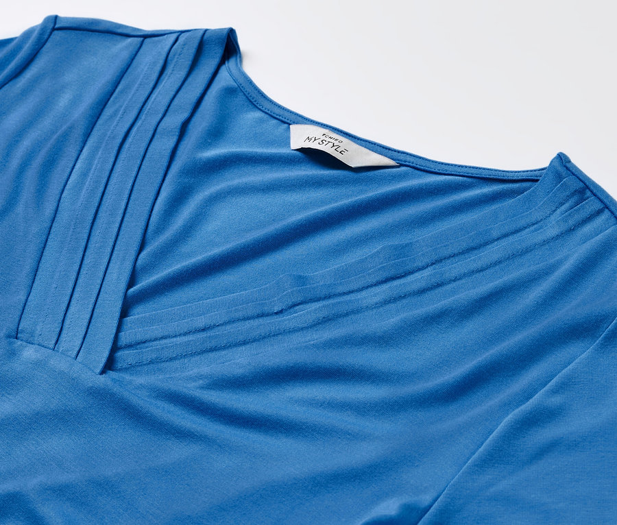 Detail modrého trička so záhybmi.