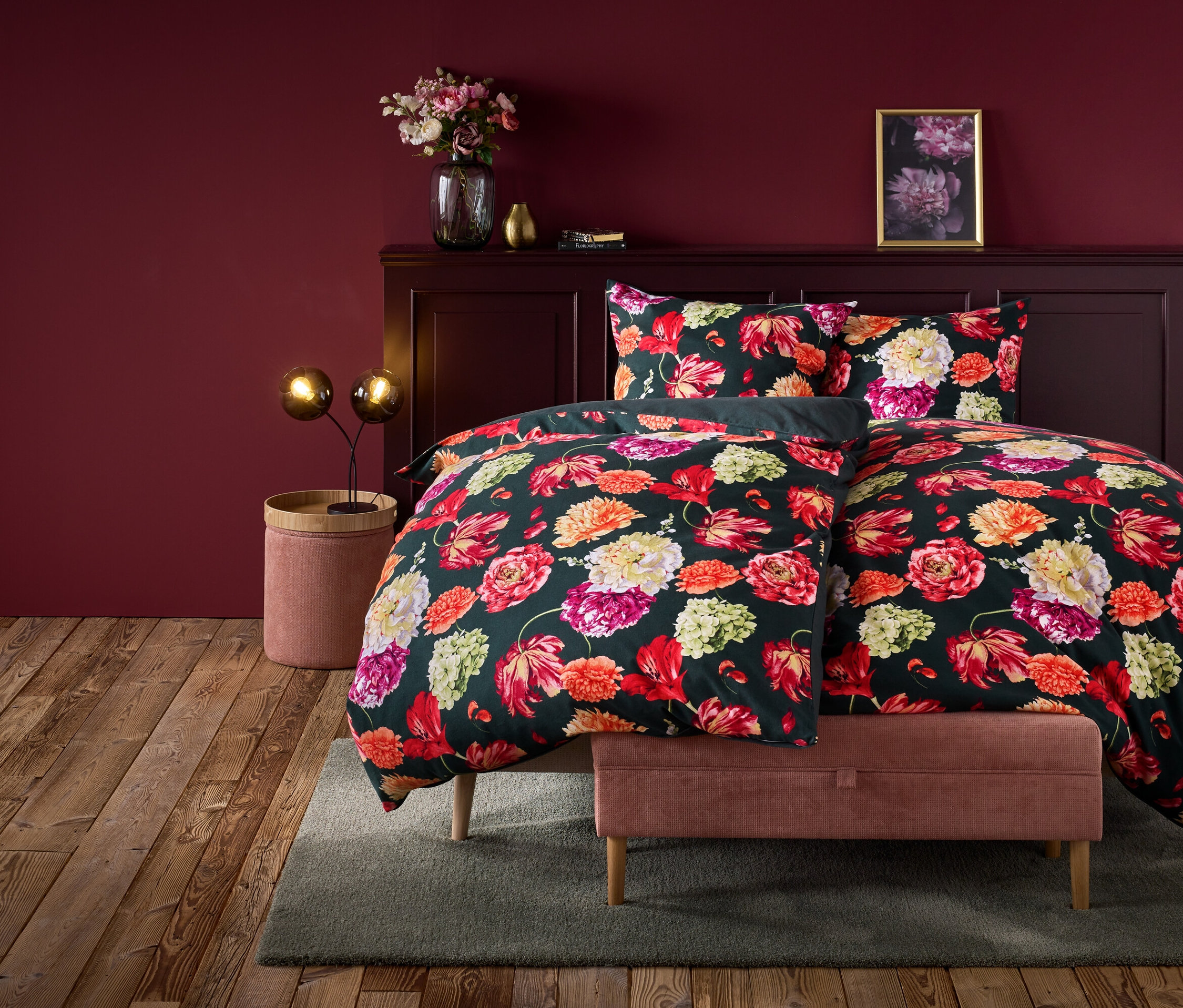 Kvetinové obliečky na posteli v izbe s vínovočervenou stenou.