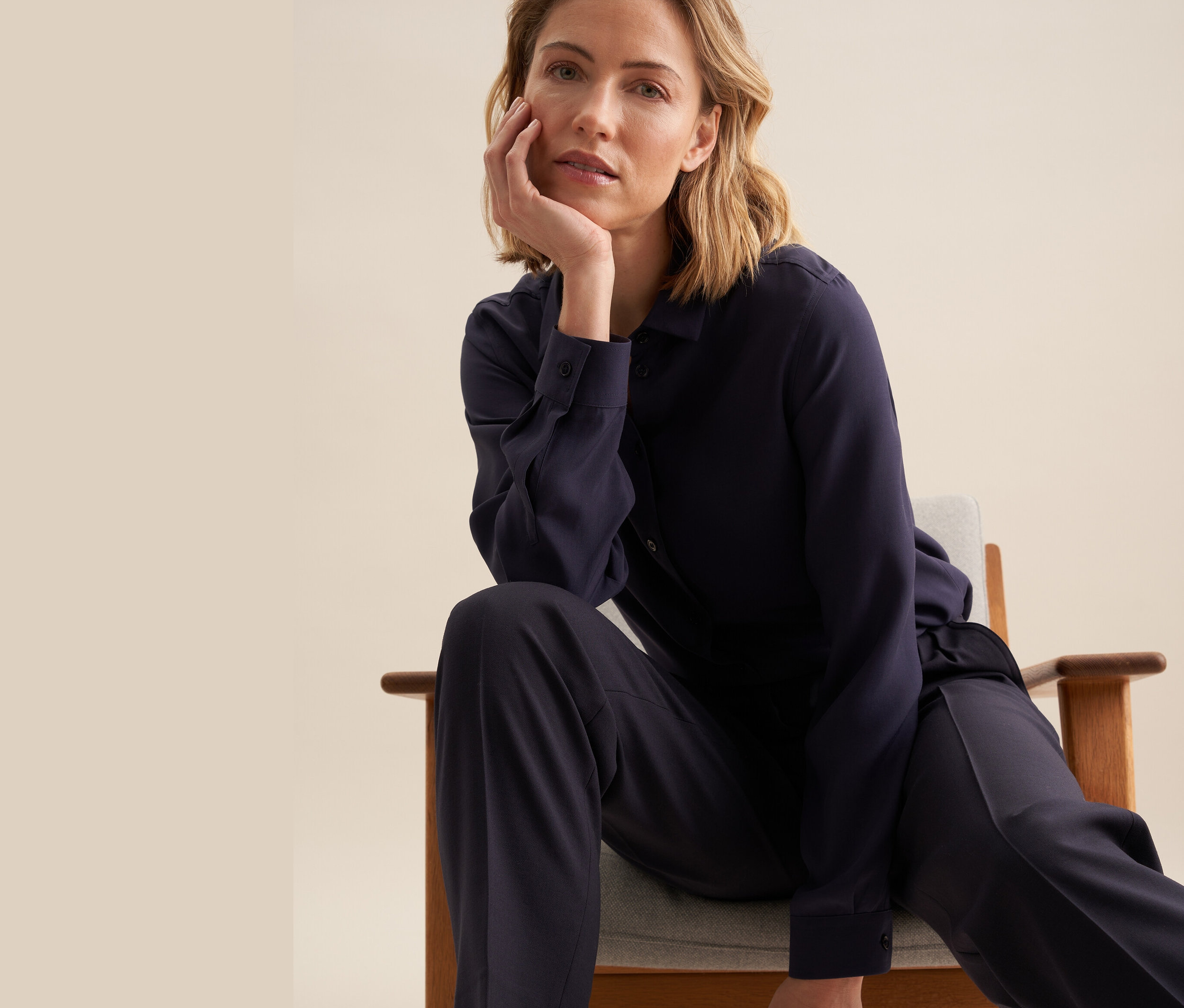 Žena sedí na stoličke a má na sebe blúzku Seidensticker z viskózy.