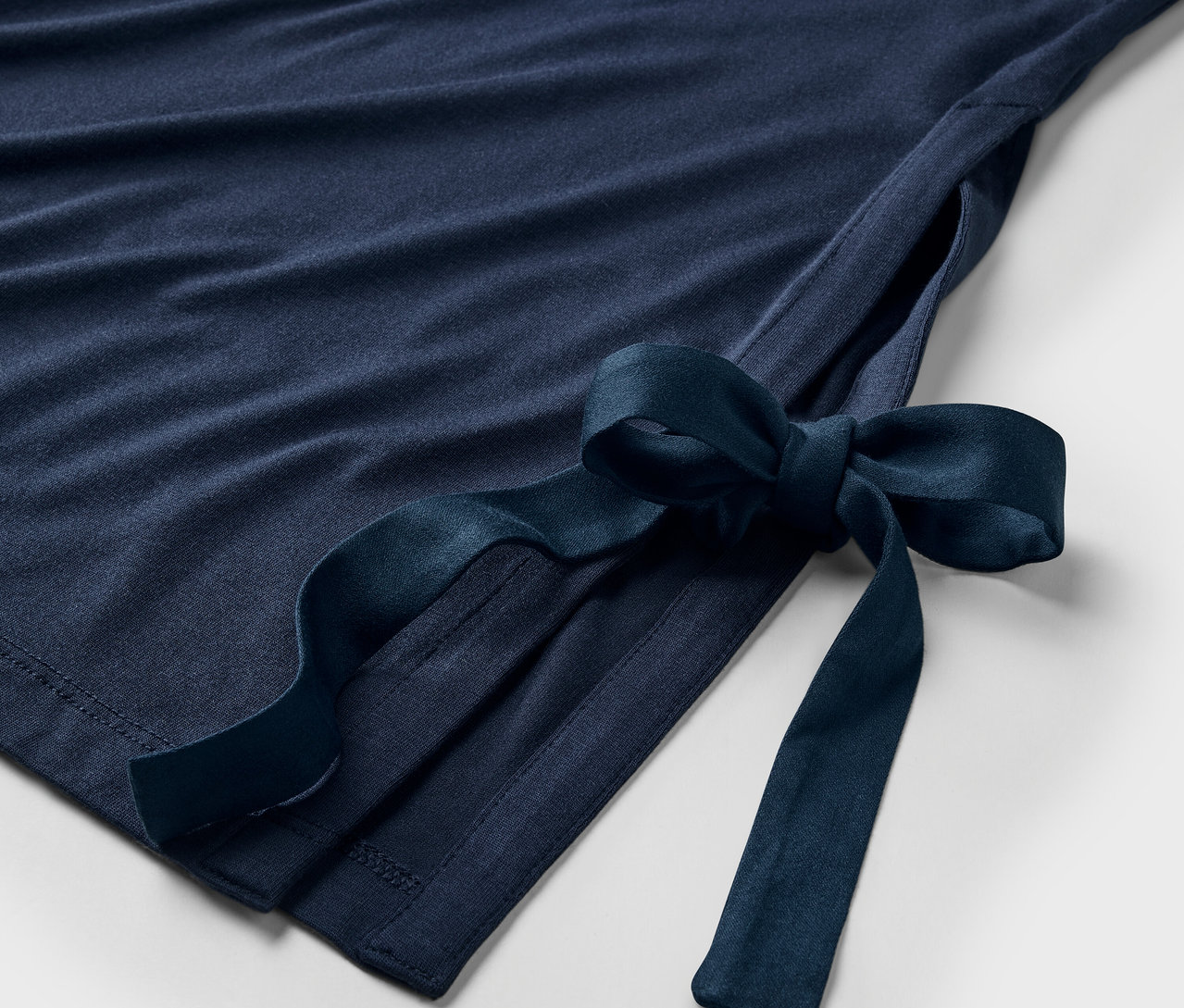 Detail tmavomodrých šiat s mašľou na boku.