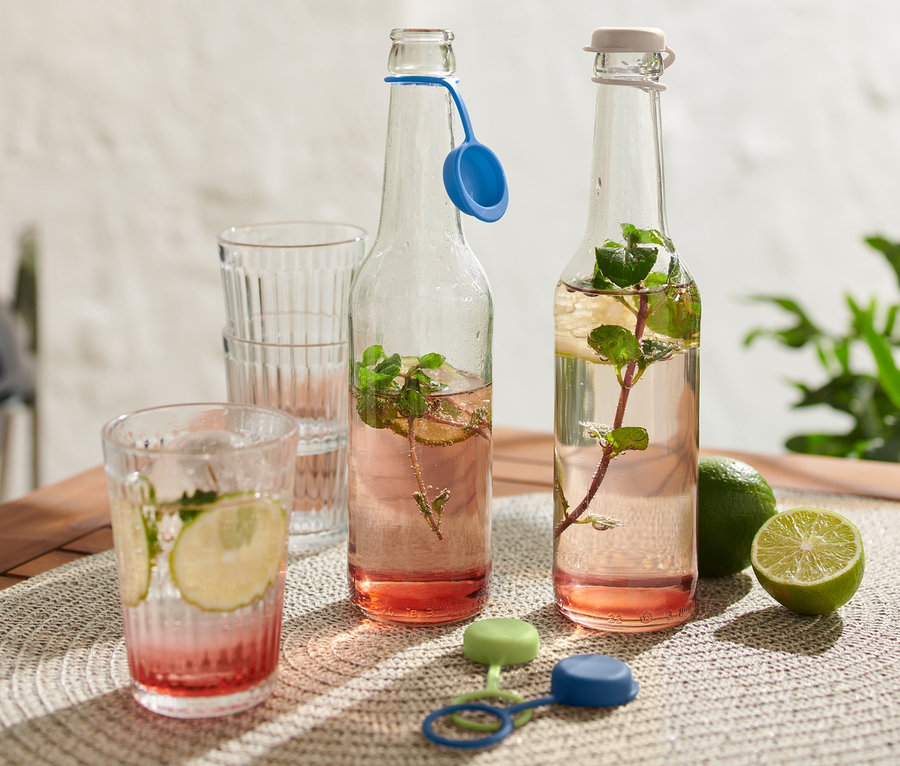 Dve fľaše s nápojom a 4 zátky na fľaše na stole.