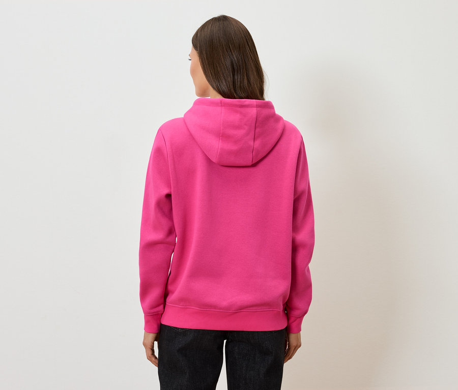 Pohľad zozadu na ženu s hnedými vlasmi v ružovej mikine s kapucňou a čiernych nohaviciach.
