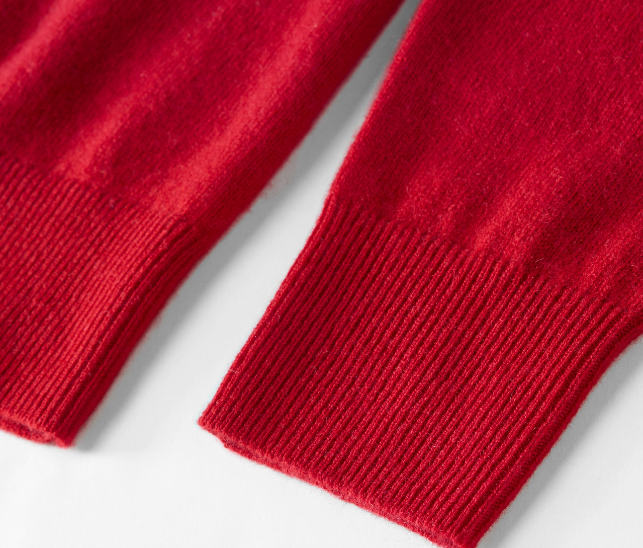 Detail červeného svetra s dlhým rukávom.