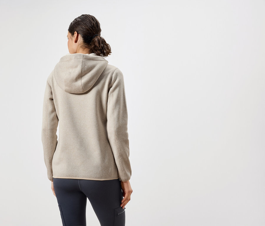 Zozadu je vidieť žena v béžovej mikine s kapucňou a tmavomodrých nohaviciach.