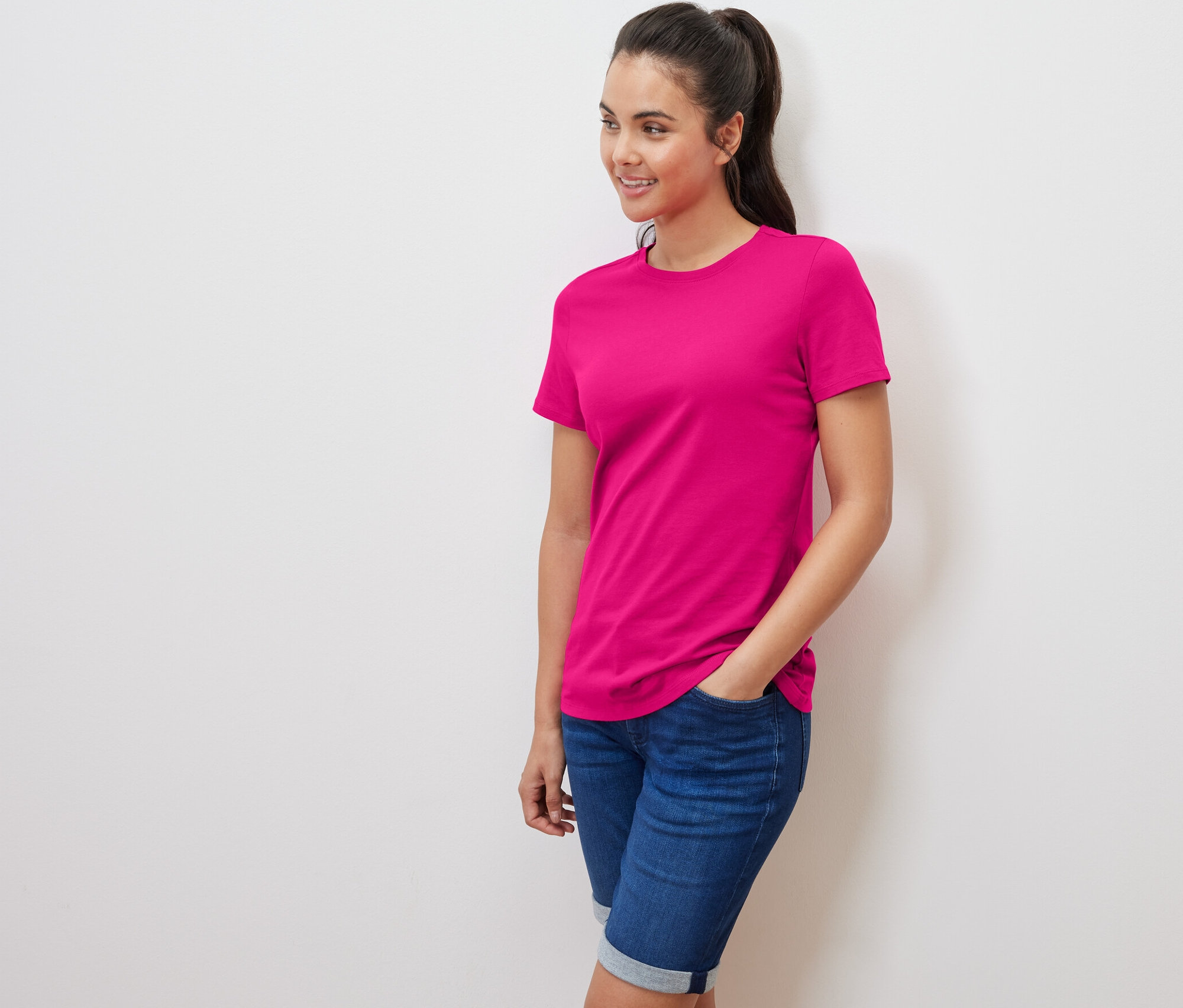 Žena pózuje v ružovom tričku.