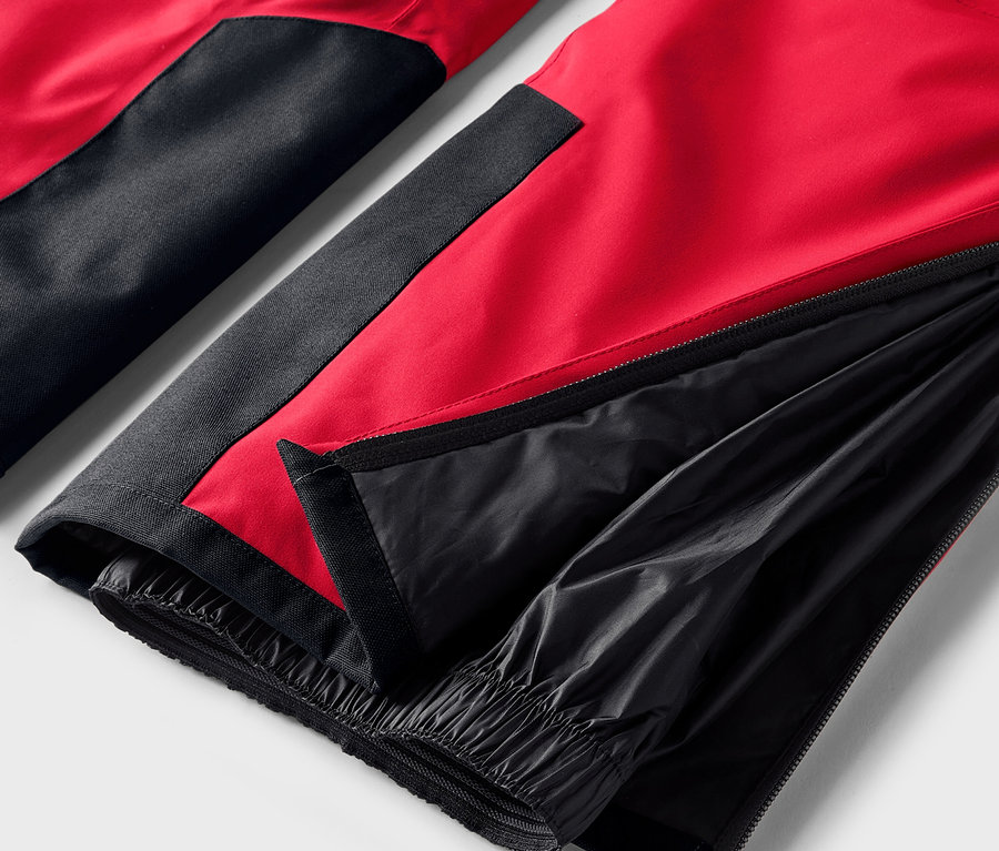 Detail červeno-čiernych nohavíc s rozopnutým zipsom na nohavici.