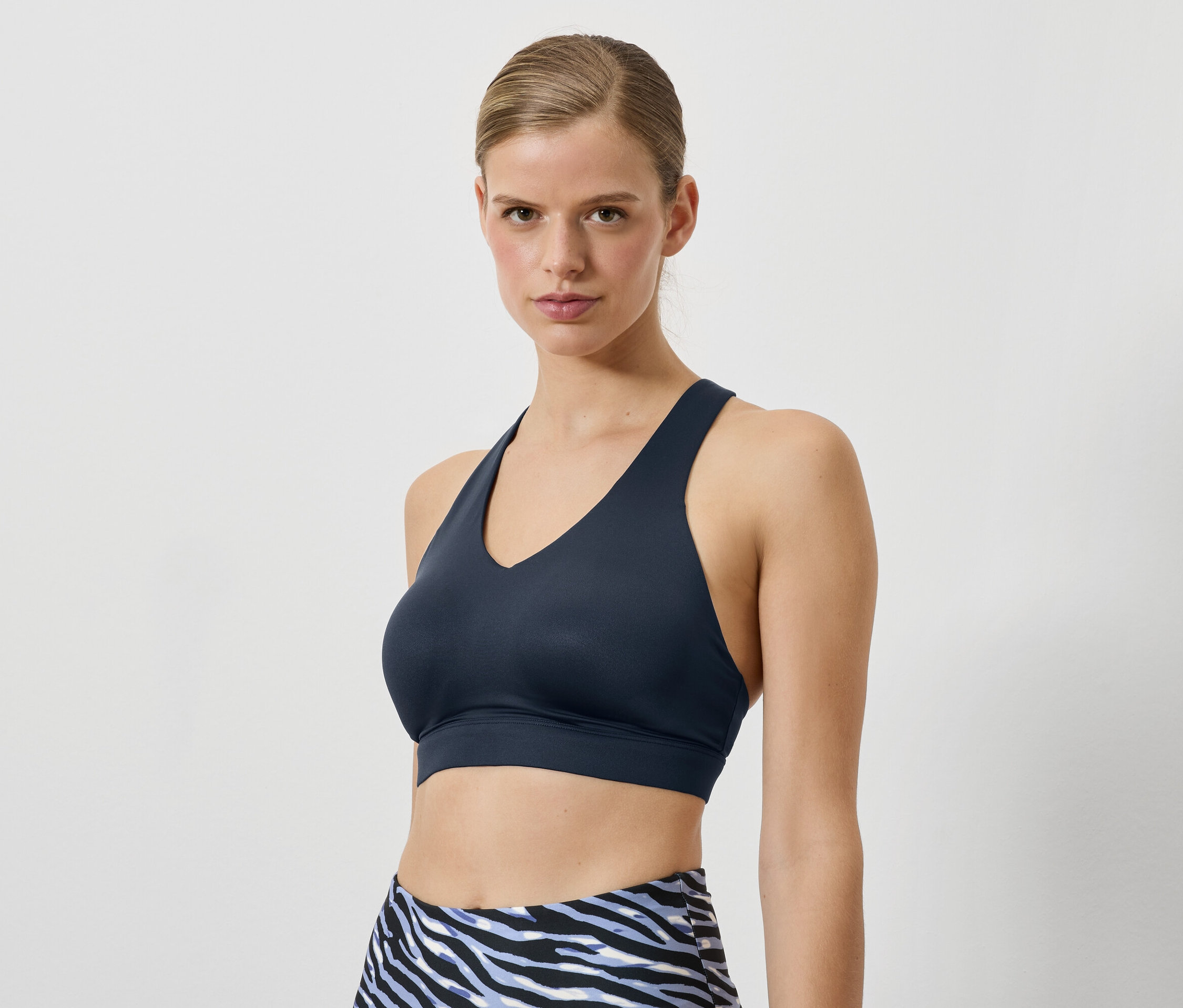 Žena má na sebe tmavomodrú športovú podprsenku a legíny so zvieracím vzorom.