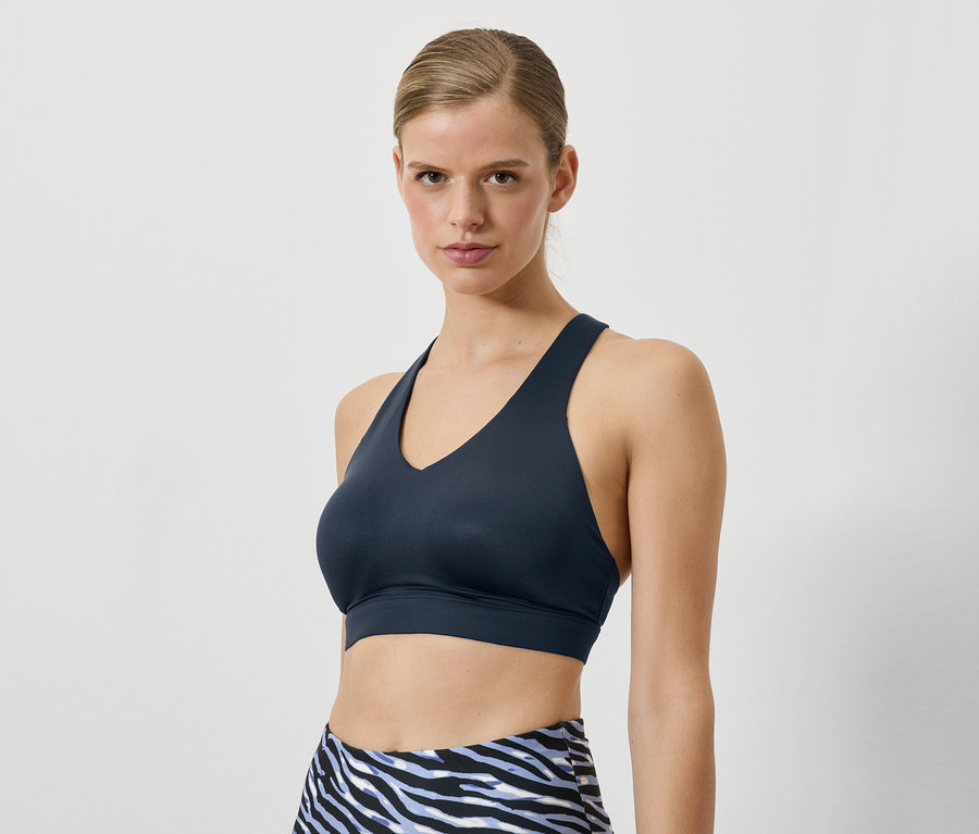 Žena má na sebe tmavomodrú športovú podprsenku a legíny so zvieracím vzorom.