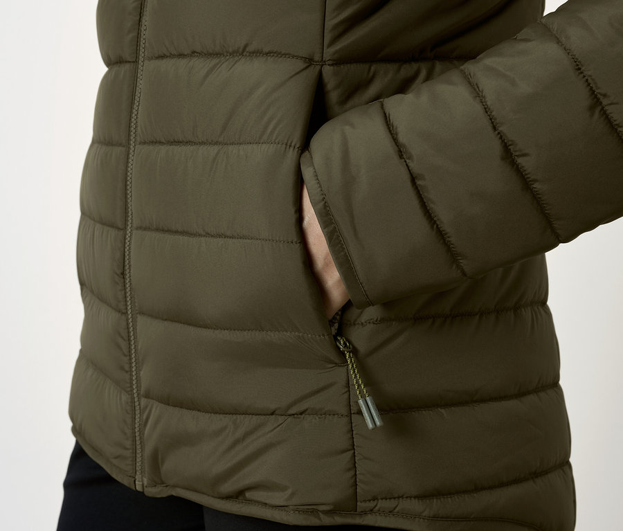Detail olivovej prešívanej bundy s rukou vo vrecku.