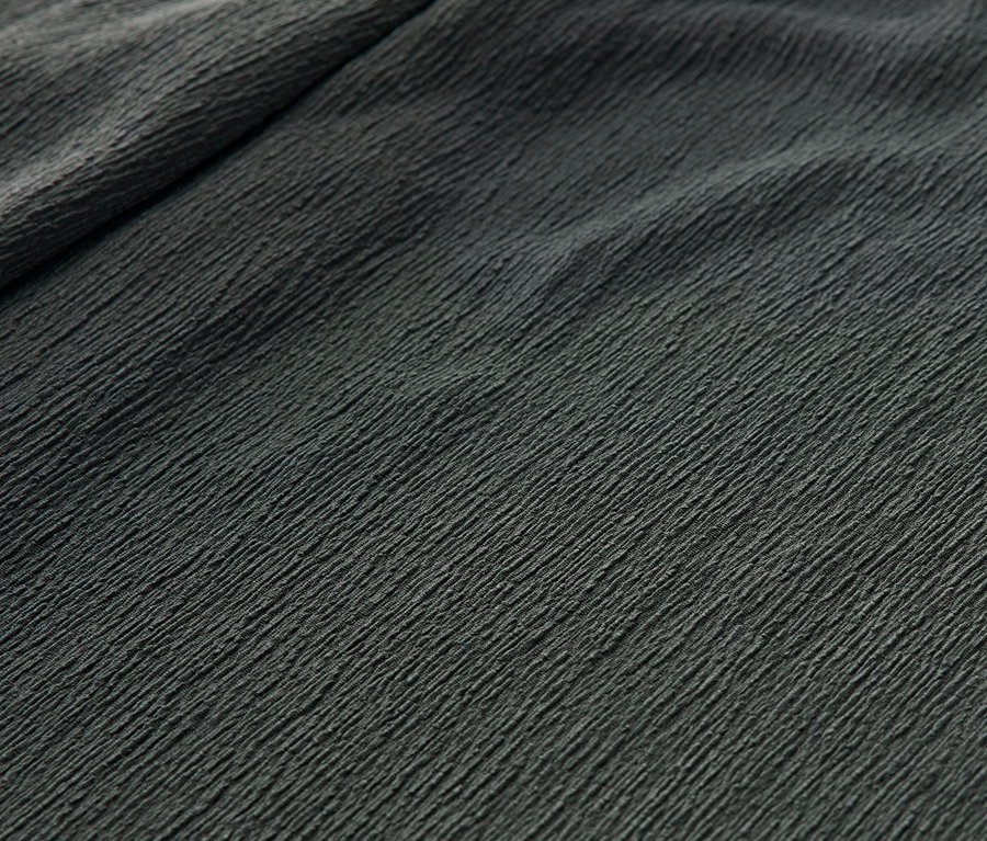 Detail zelených pohodlných nohavíc v pokrčenom vzhľade.