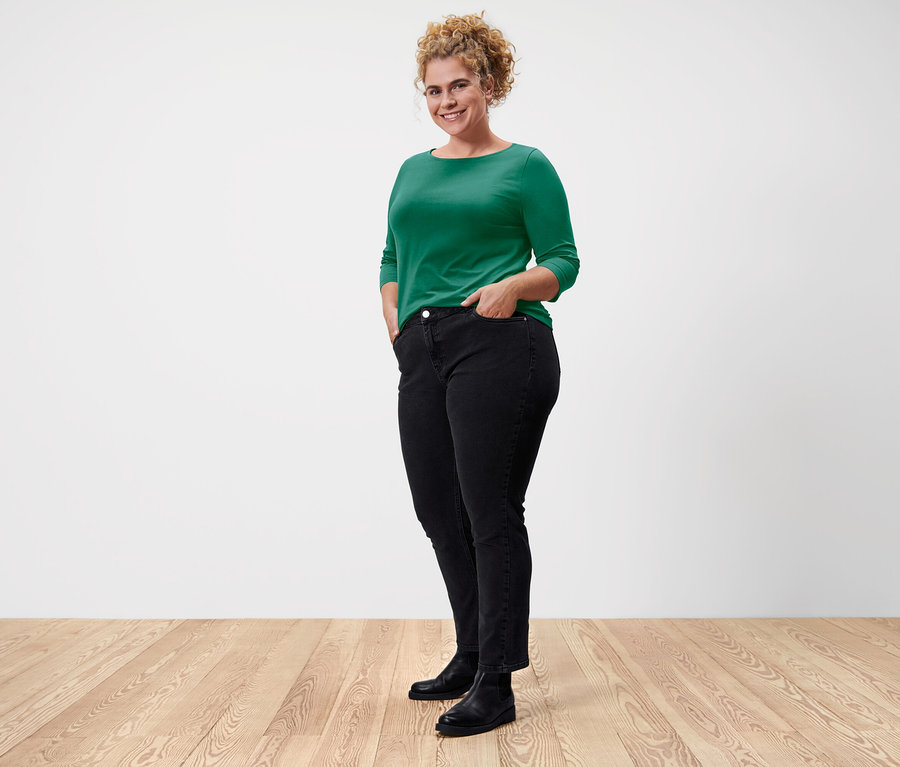 Žena pózuje v zelenom tričku s trojštvrťovým rukávom.