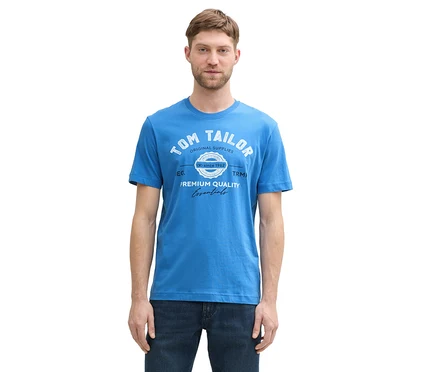 Muž má na sebe tričko s logom Tom Tailor, sapphire blue a džínsy.