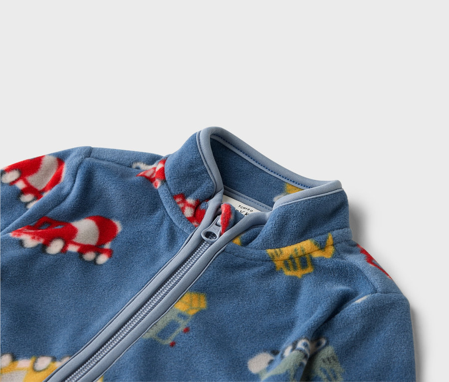 Detailný záber na modrú fleecovú bundu na zips s farebnými motívmi vozidiel.