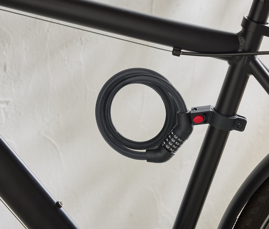 Čierny bicykel má na ráme pripevnený špirálový káblový zámok s číselným kódom.