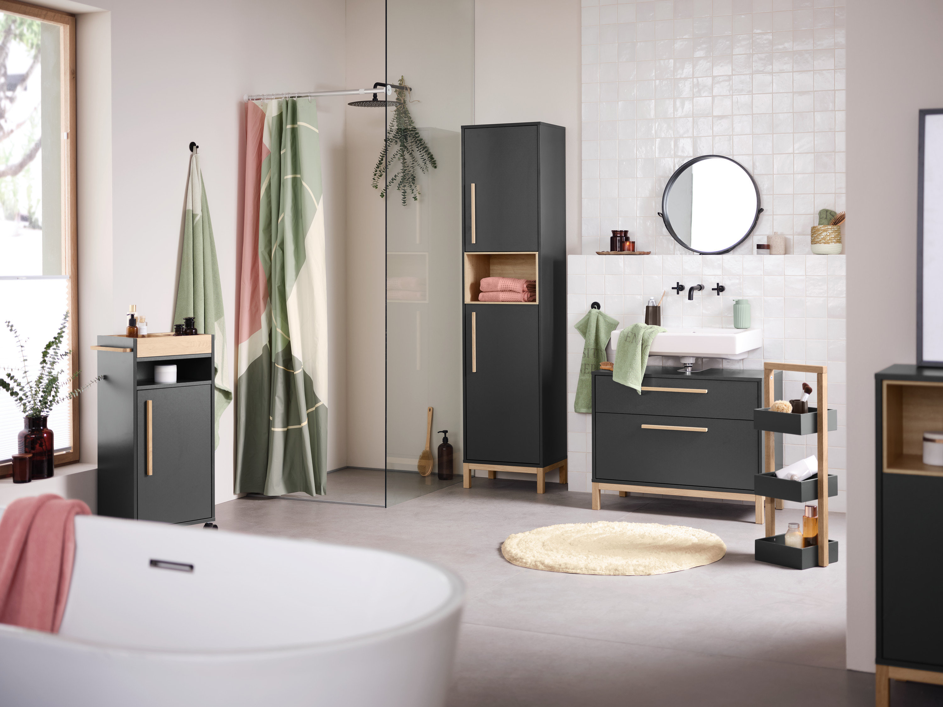 Interiér kúpeľne s umývadlom, zrkadlom a úložnými skrinkami Eklund v antracitovej farbe. V popredí je vaňa.