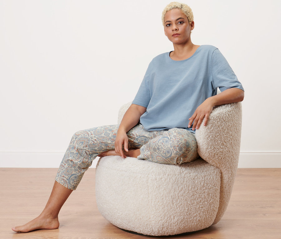 Žena sedí v kresle a má na sebe pyžamo v sedemosminovej dĺžke.