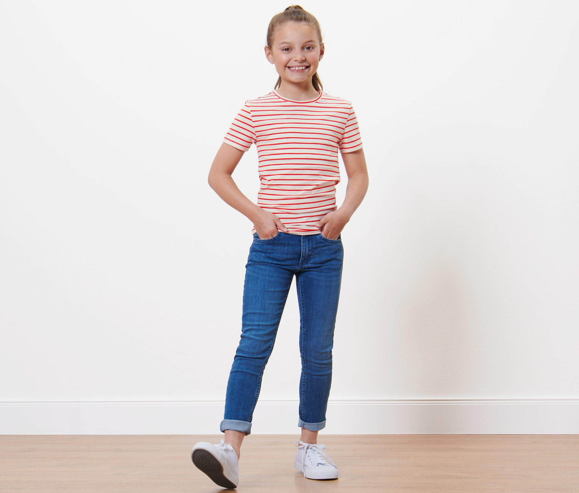 Dievča v tričku s červenými pruhmi a džínsoch stojí s rukami vo vreckách. Detské tričká, 3 ks.