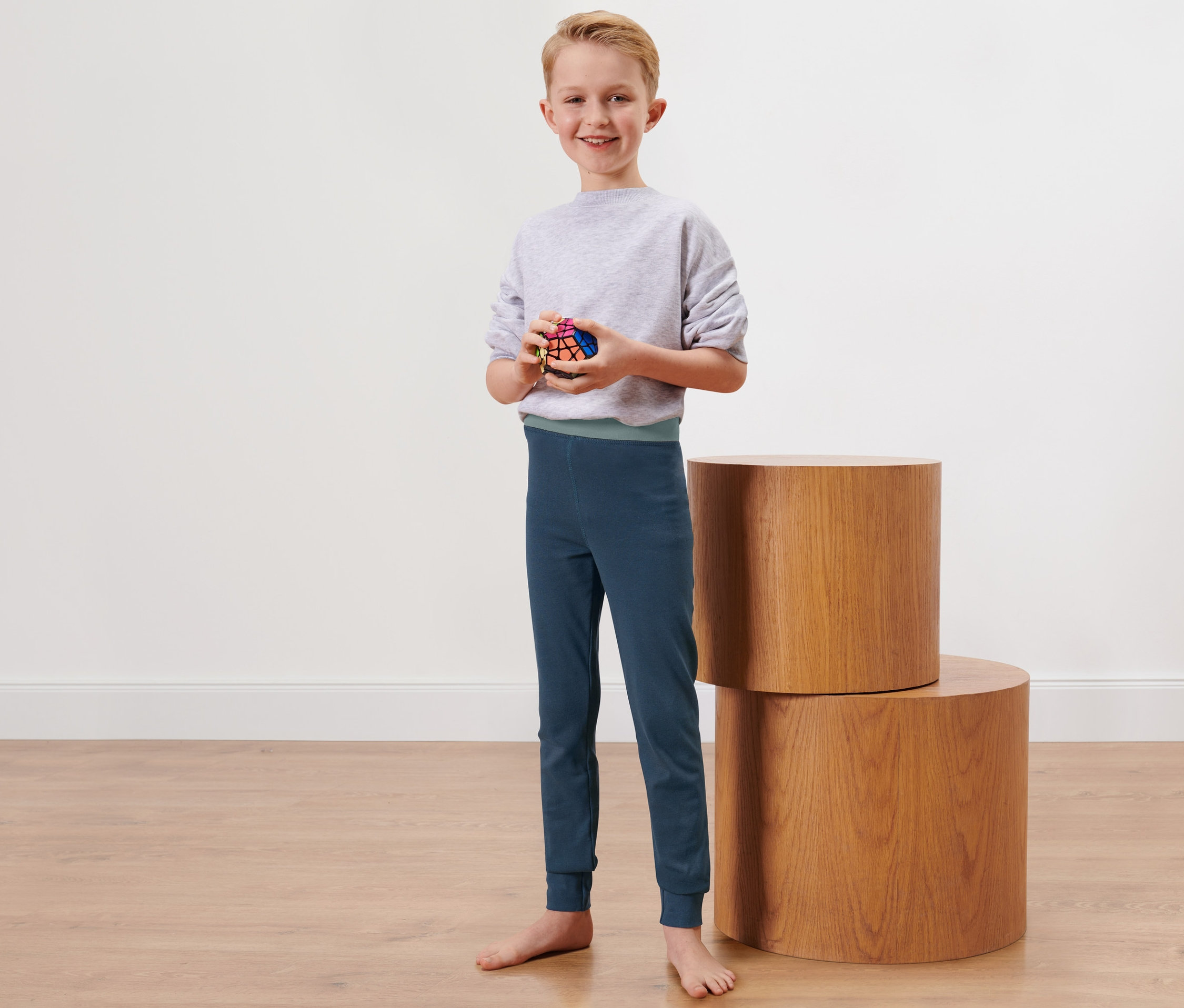 Chlapec stojí a drží Rubikovu kocku. Má na sebe detské dlhé zimné spodky.
