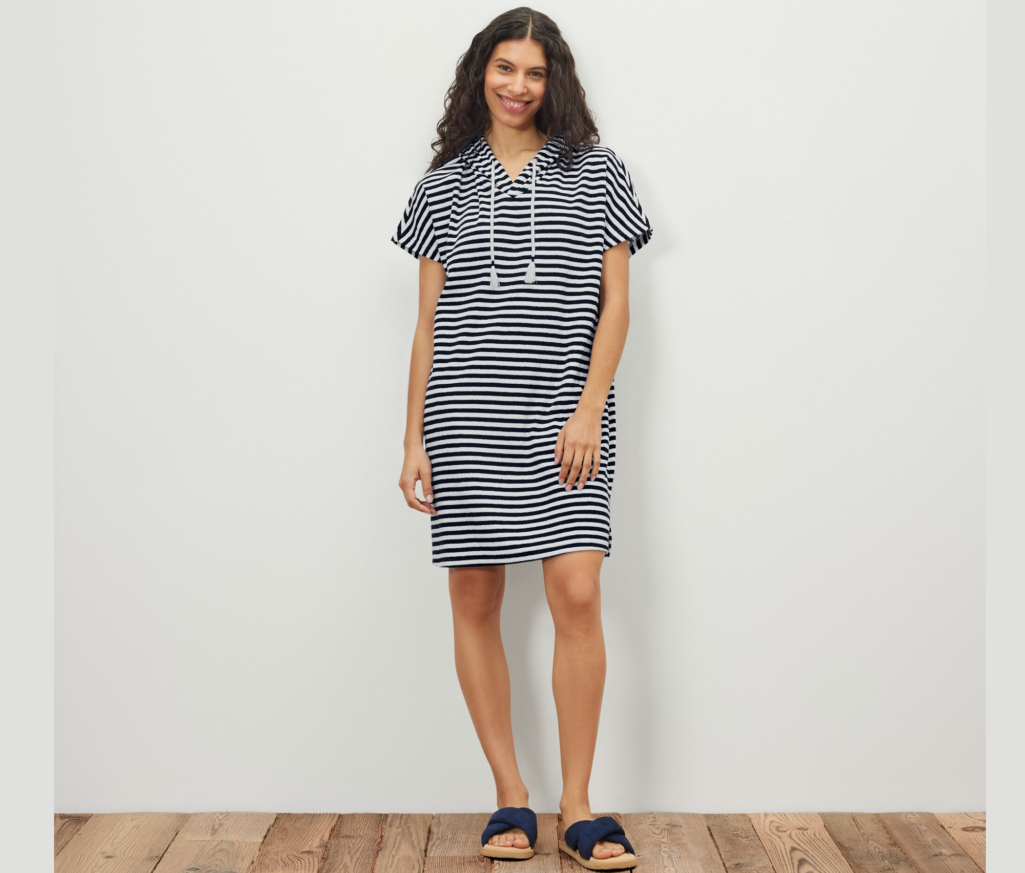 Žena pózuje v prúžkovaných plážových froté šatách.