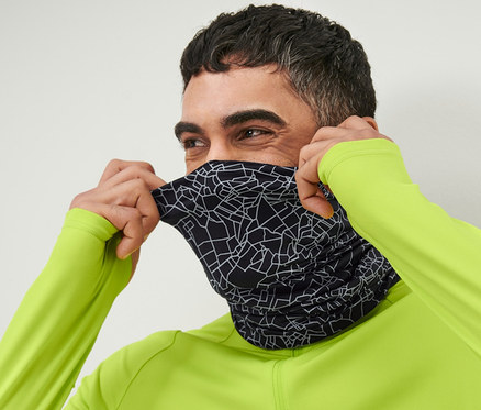 Muž si preťahuje cez tvár multifunkčnú čiernu šatku s reflexnou potlačou.