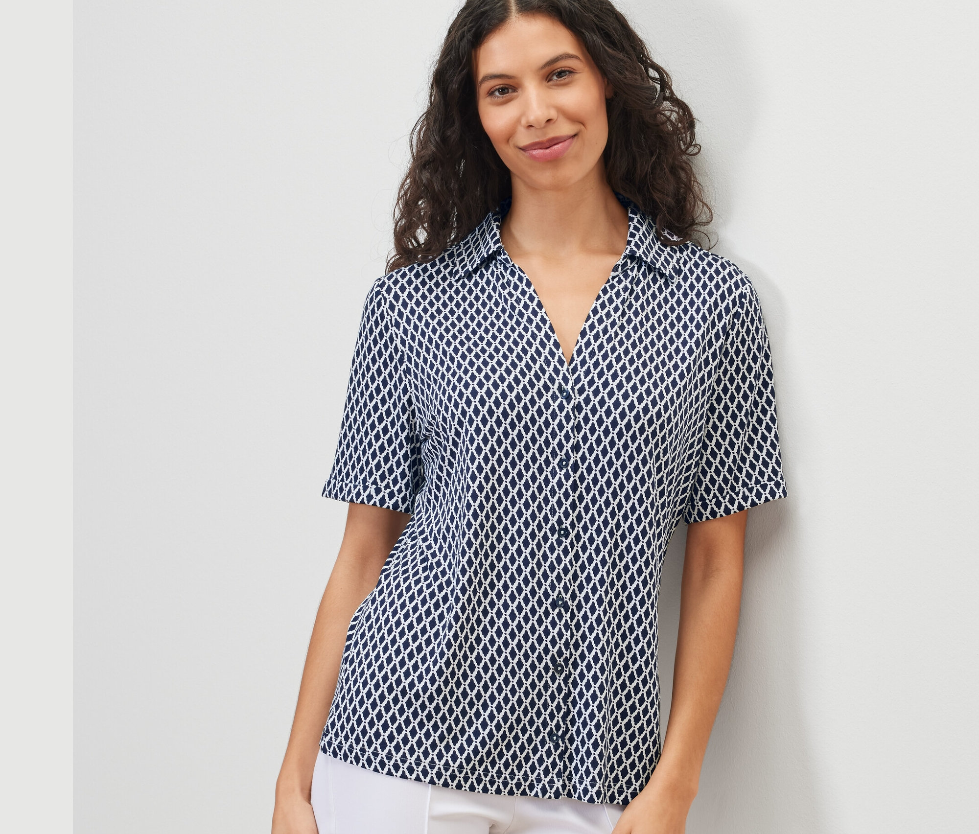 Žena má na sebe blúzkové tričko s potlačou s gombíkovou légou.